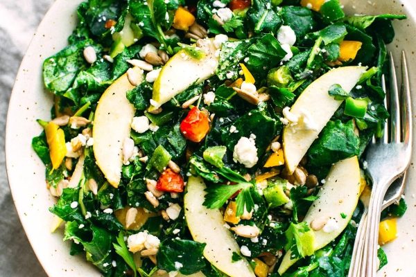 A bowl of kale salad with pears and pecans.