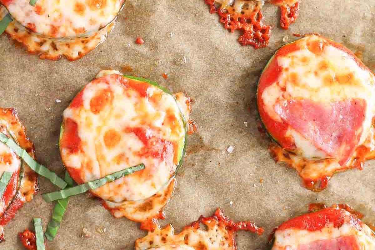 A baking sheet with a tray of cheese, pepperoni, and zucchini pizza crackers.