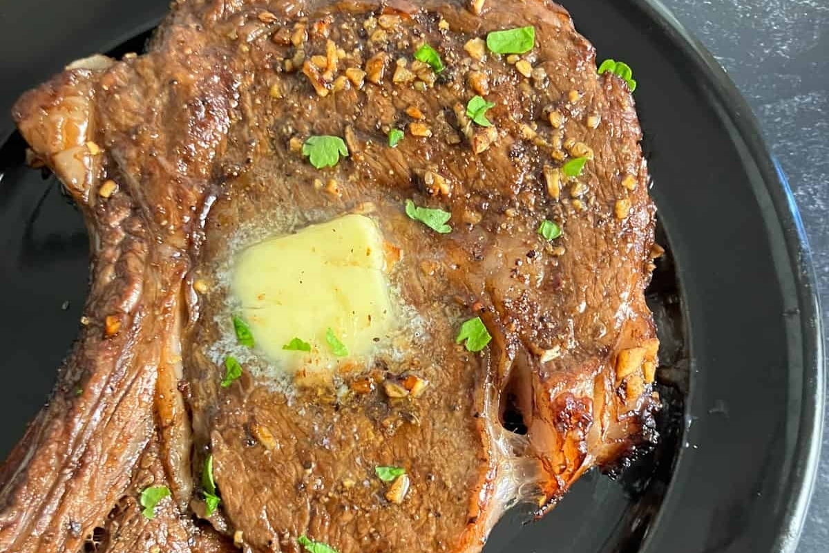 A winter recipe featuring a perfectly cooked steak with butter and herbs, presented on a sleek black plate.