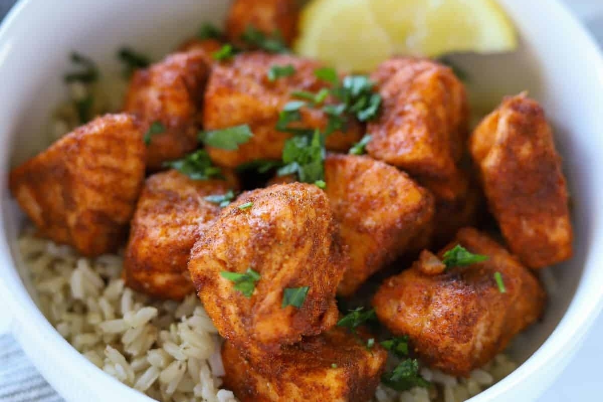 A bowl of rice with chicken and lemon wedges.