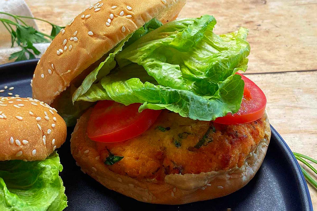 Two burgers with lettuce and tomatoes on a black plate.