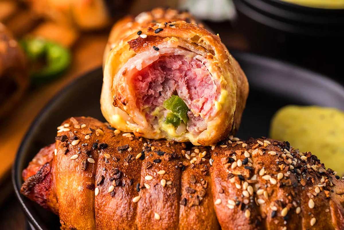 A plate of meat wrapped in a crescent roll with dipping sauce.