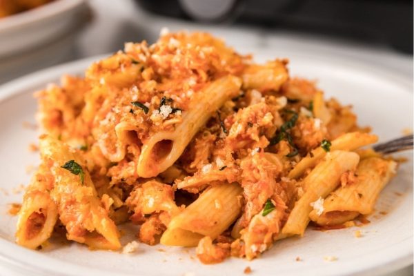 A plate of pasta with chicken and cheese on it.