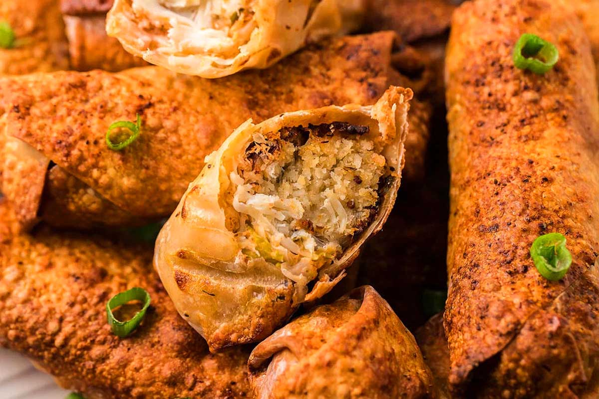 Chinese spring rolls on a plate with green onions.