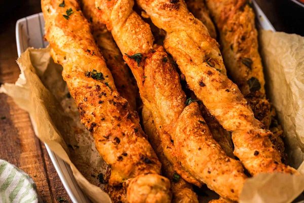 Cheesy garlic bread sticks in a basket on a wooden table, perfect for your next gathering.