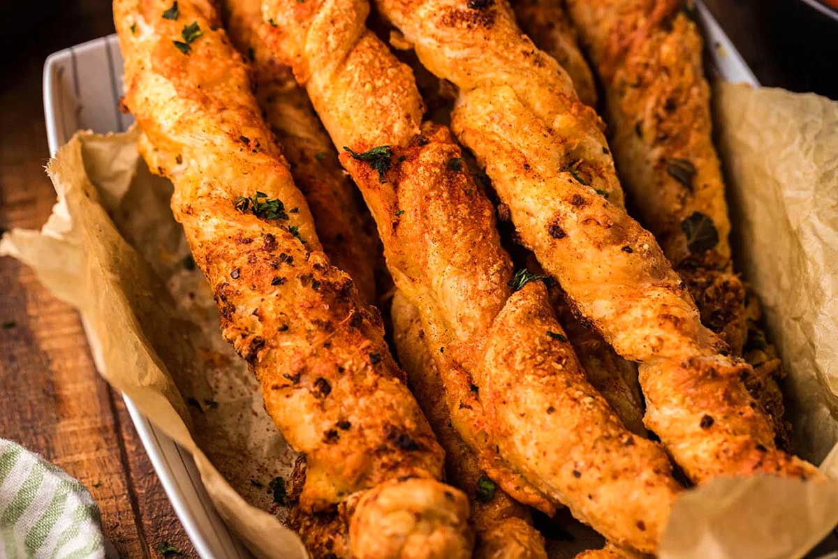 Cheesy garlic bread sticks in a basket on a wooden table, perfect for your next gathering.