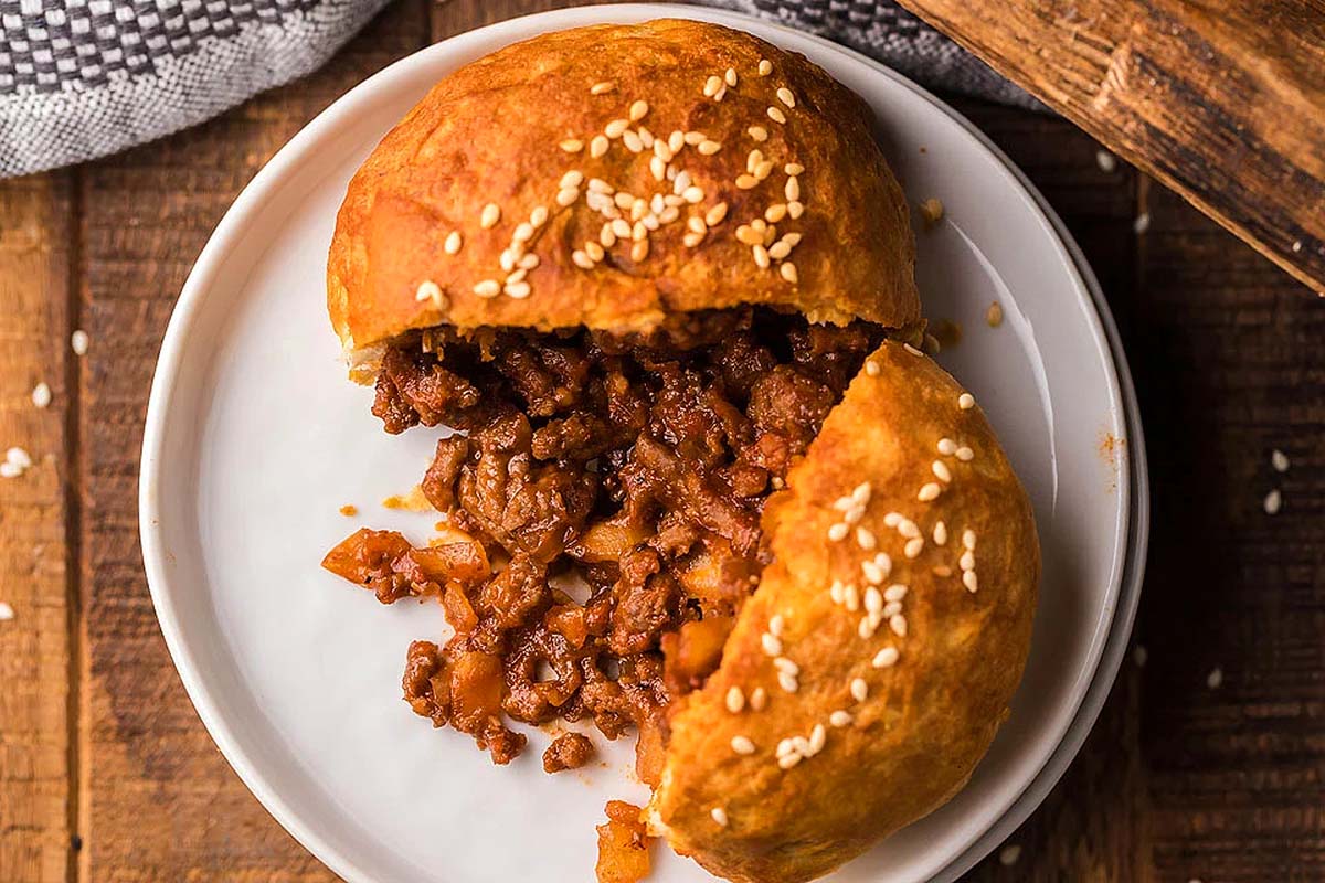 A delicious meatball sandwich on a plate, topped with sesame seeds.