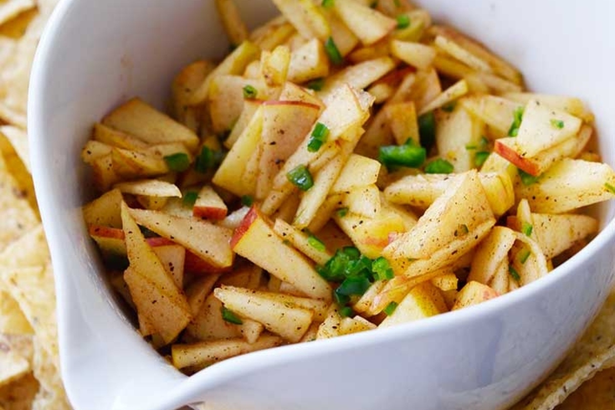 Apple salsa in a white bowl with tortilla chips.