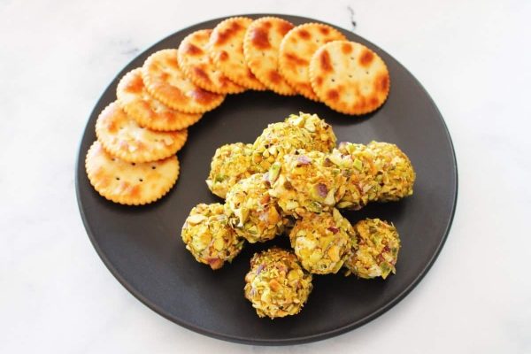 A black plate with cheese ball and crackers.