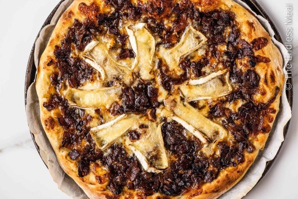 A cheese pizza with onions on a plate.