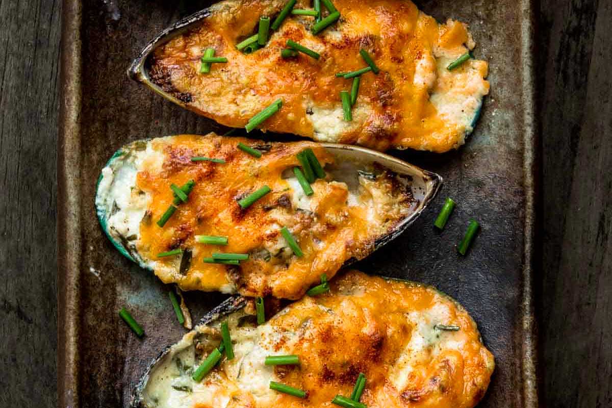 Stuffed clams with cheese and chives on a plate.