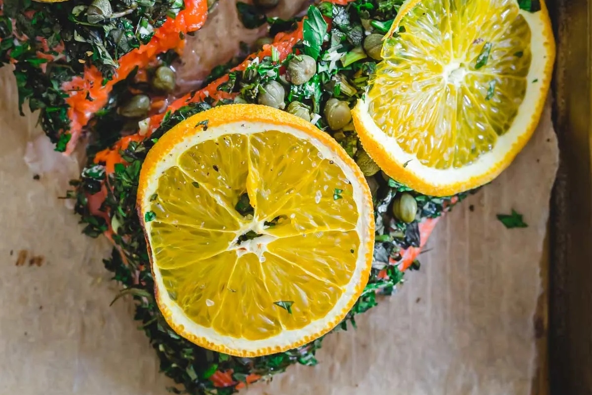 Salmon with orange slices on a baking sheet.