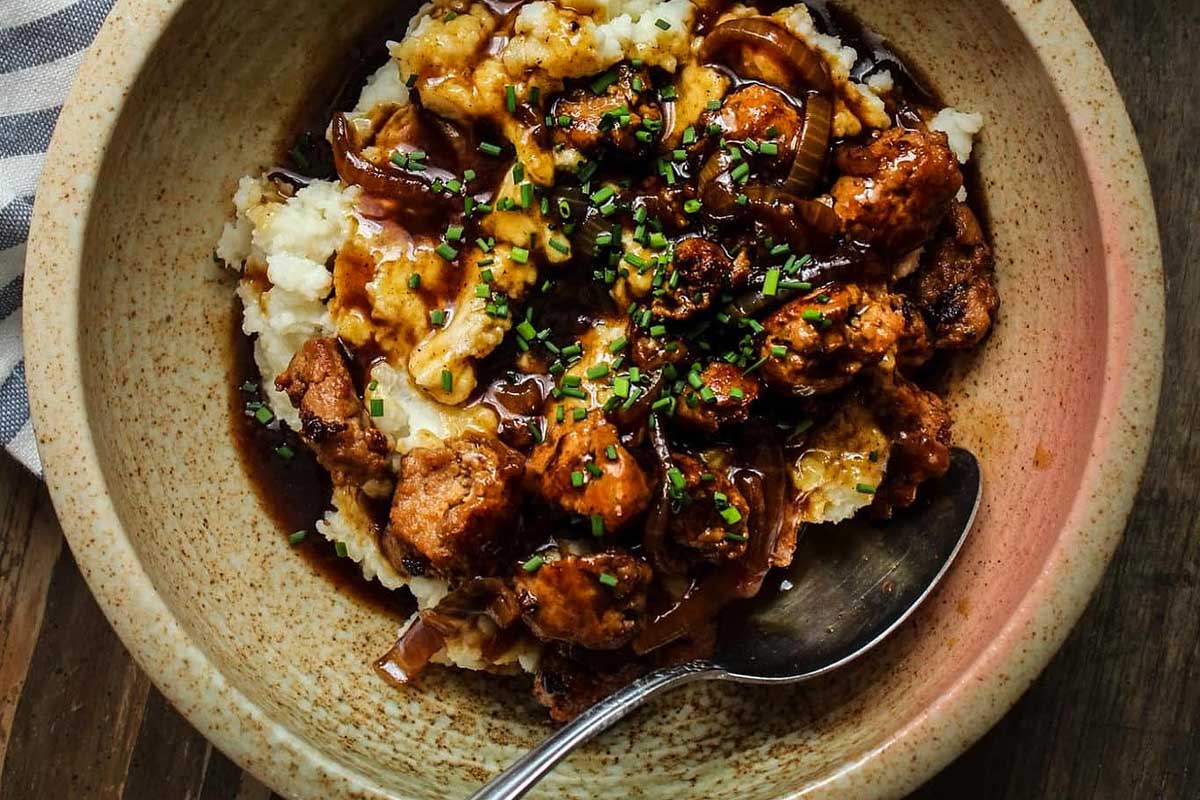 A hearty pub and bar food favorite, enjoy a steaming bowl of mashed potatoes smothered in rich gravy and topped with tender meat.