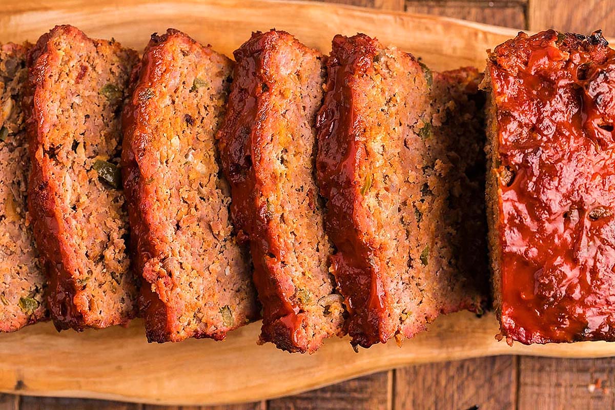 Deliciously sliced meatloaf on a rustic wooden cutting board.
