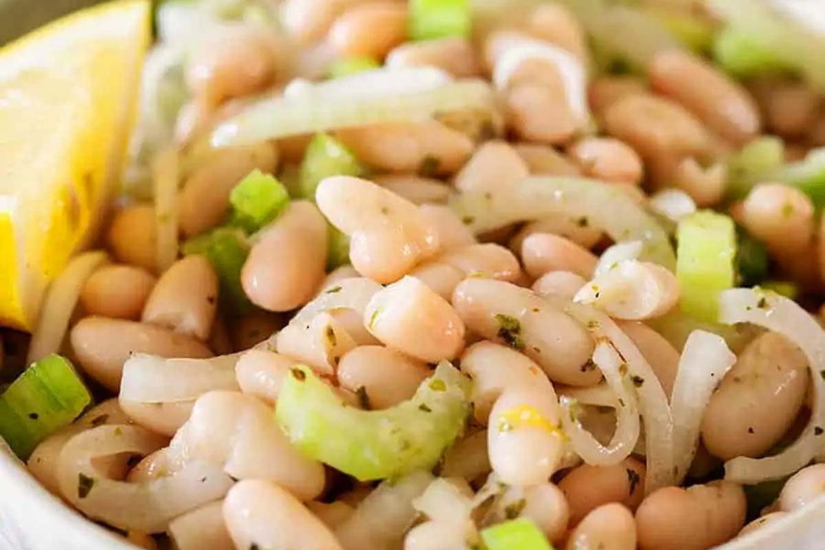 Italian white bean salad recipe served in a white bowl with a lemon wedge.