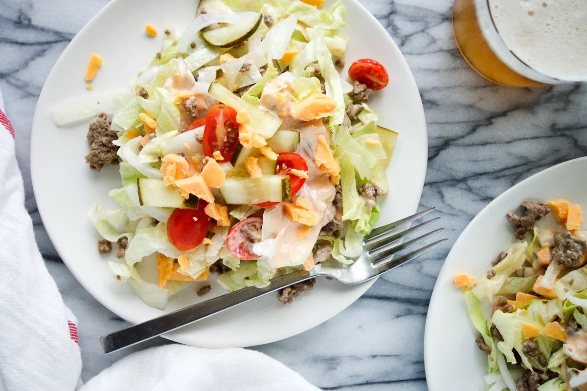 A plate with a salad and a beer on it.