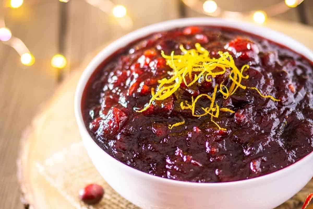 A delectable bowl of cranberry sauce awaits on a rustic wooden table, ready to enhance your holiday recipes.