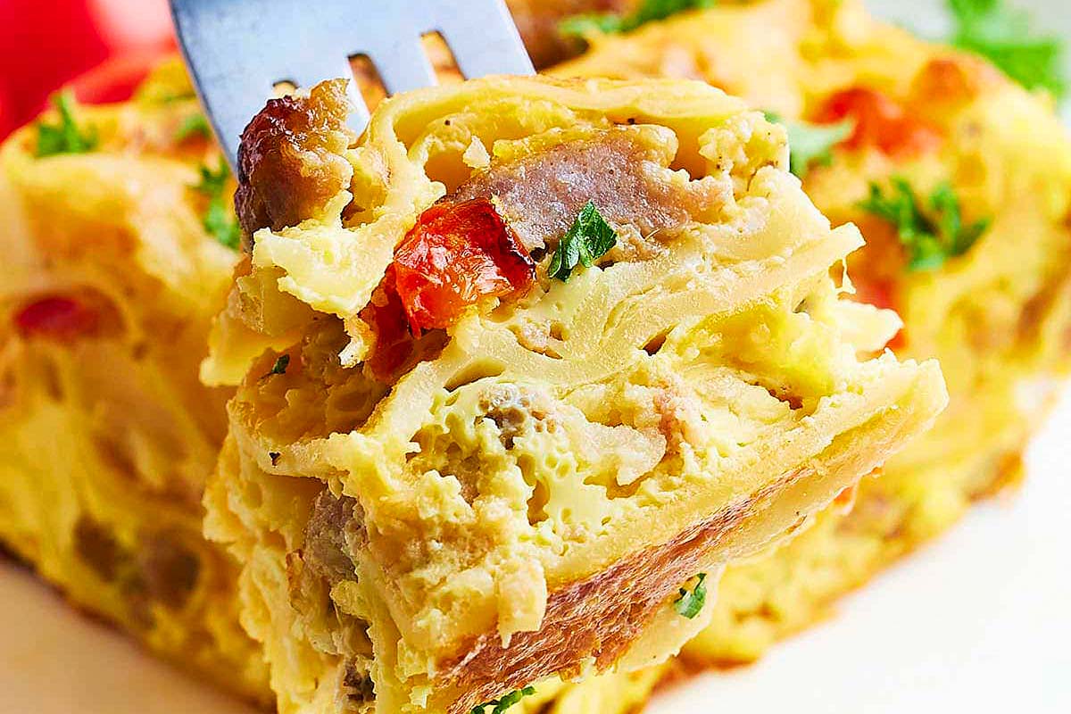 A fork is being used to take a bite out of a piece of breakfast casserole.