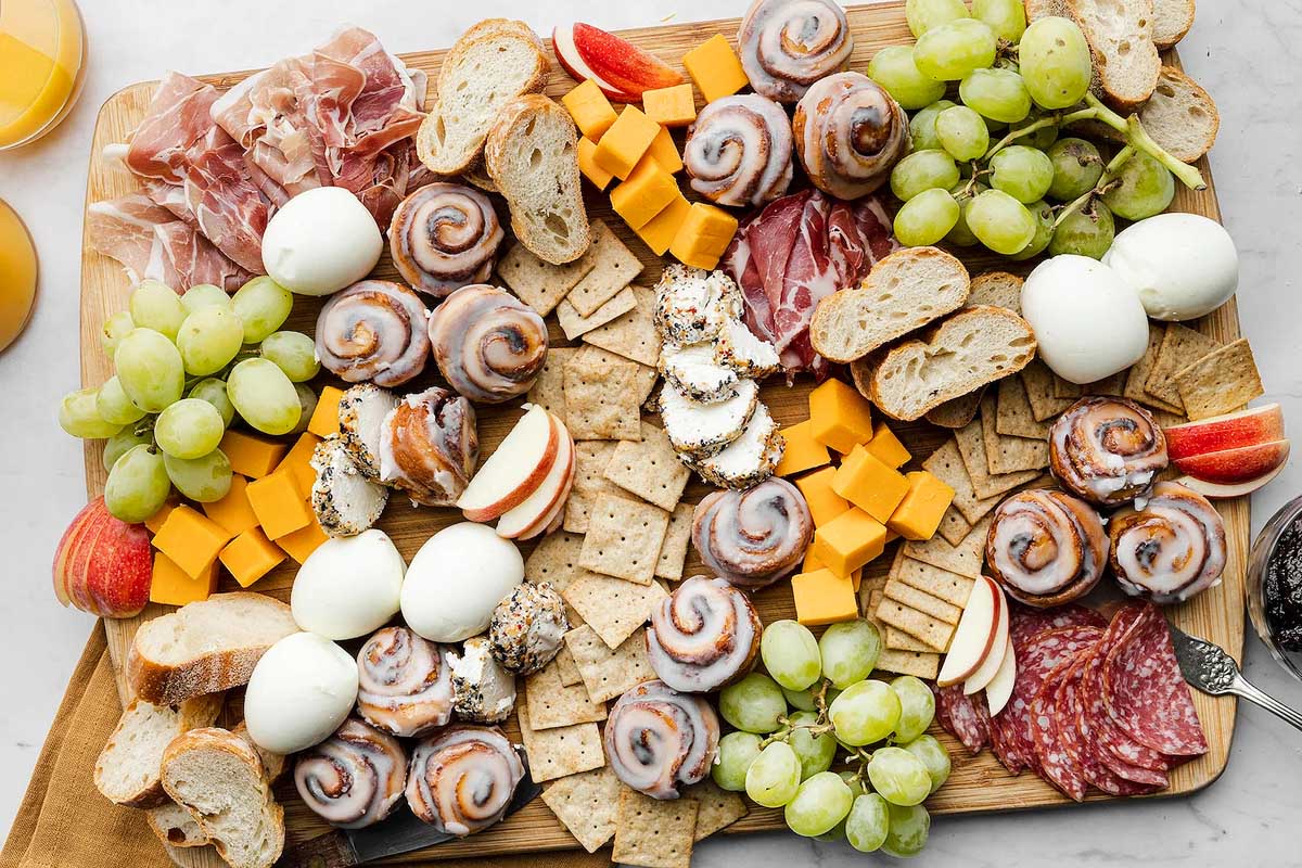 A mouthwatering display of meats and cheeses on a rustic wooden board, perfect for brunch gatherings.