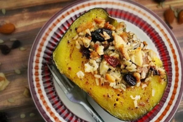 A stuffed squash with nuts and raisins on a Thanksgiving plate.