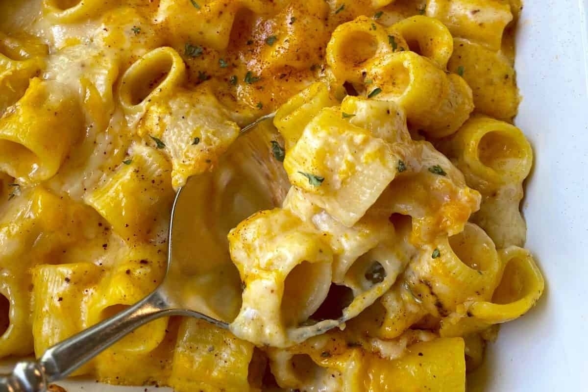 A spoonful of cheesy macaroni and cheese in a casserole dish, perfect as a side dish.