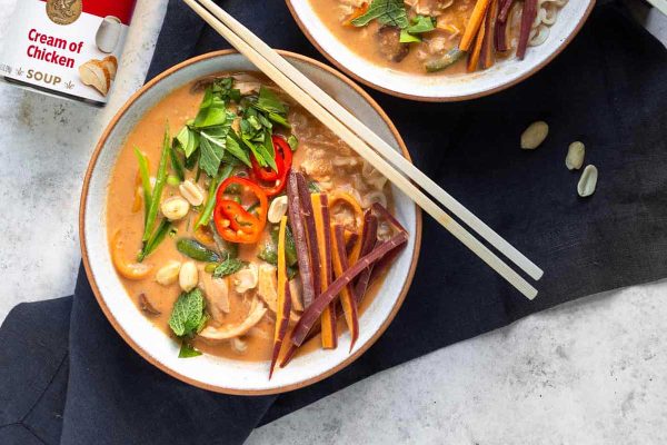 Two bowls of thai noodle soup with chopsticks.