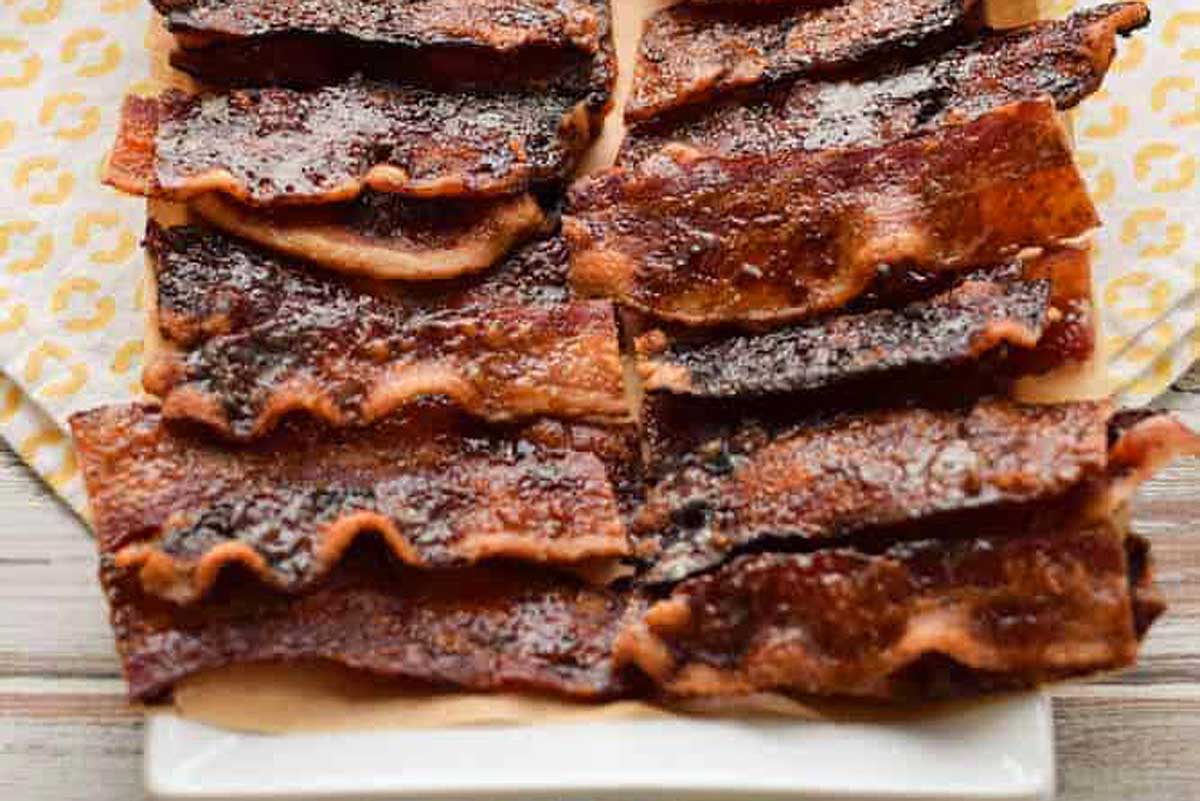 Bacon on a white plate with a yellow napkin.