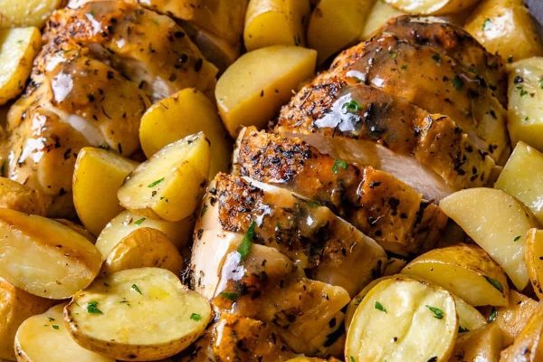 Bone-in chicken breasts with potatoes and gravy in a skillet.
