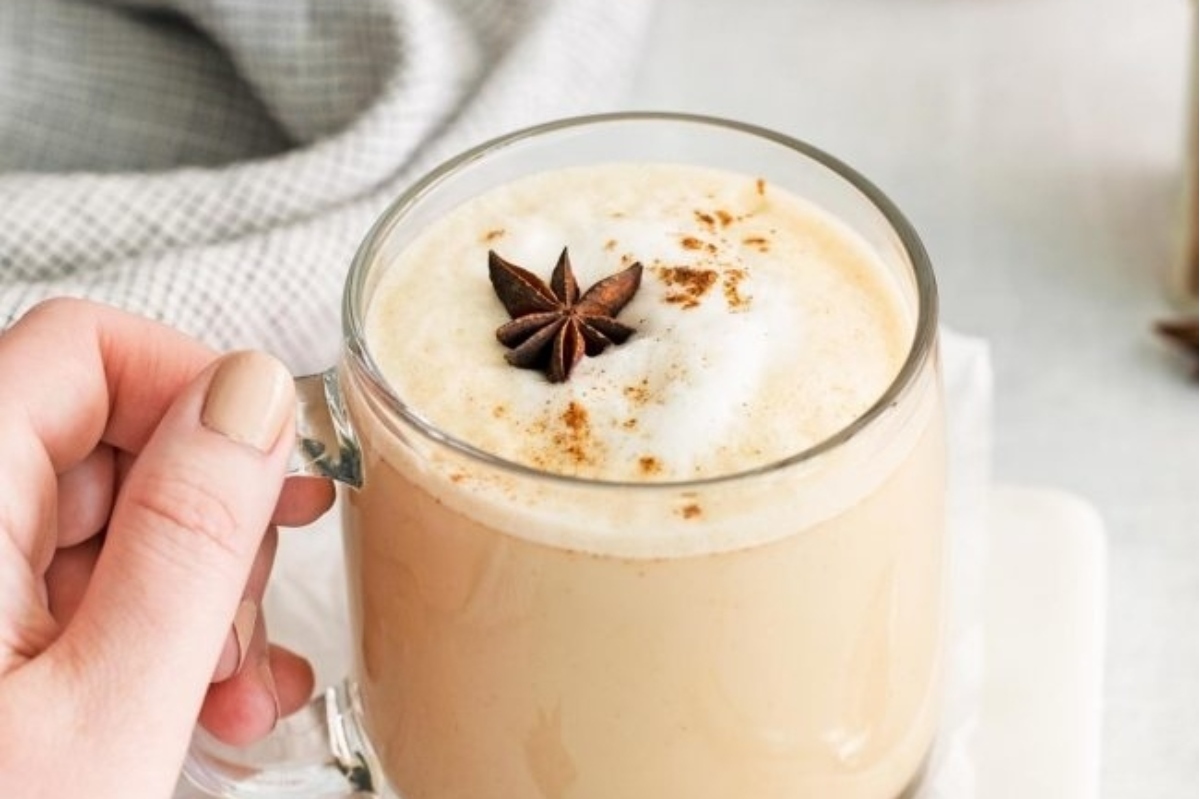 A person enjoying a festive cup of coffee with cinnamon and star anise, perfect for the holiday season.