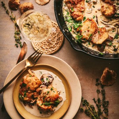 Champagne chicken in a skillet on a table next to a plate.