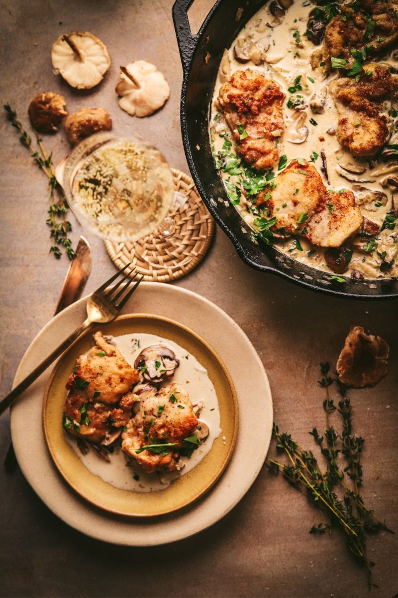 Champagne chicken in a skillet on a table next to a plate.