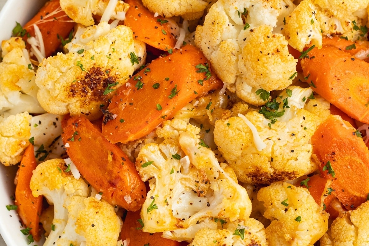 Roasted cauliflower and carrots served as a flavorful side dish in a white bowl.