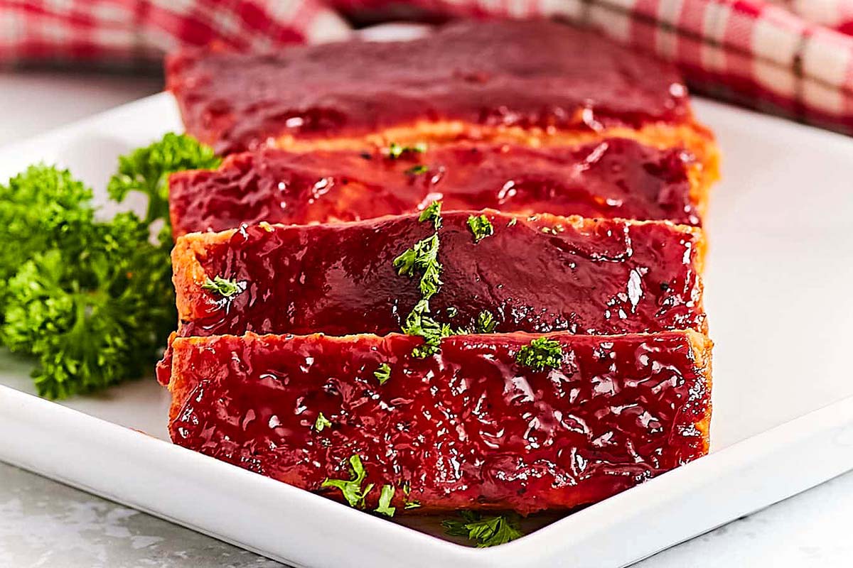 Delicious meatloaf with a savory sauce elegantly presented on a pristine white plate.
