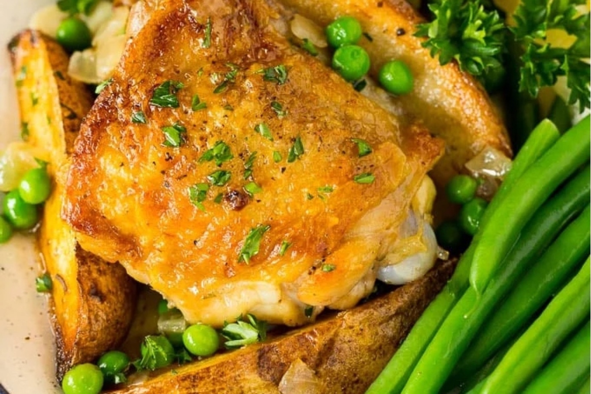 Chicken with frozen peas and potatoes on a plate.