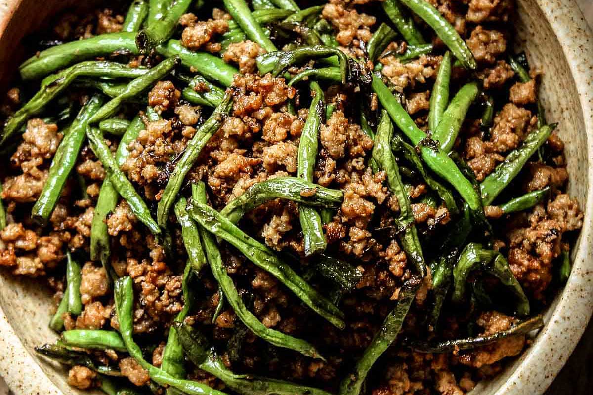 A bowl filled with green beans and meat.