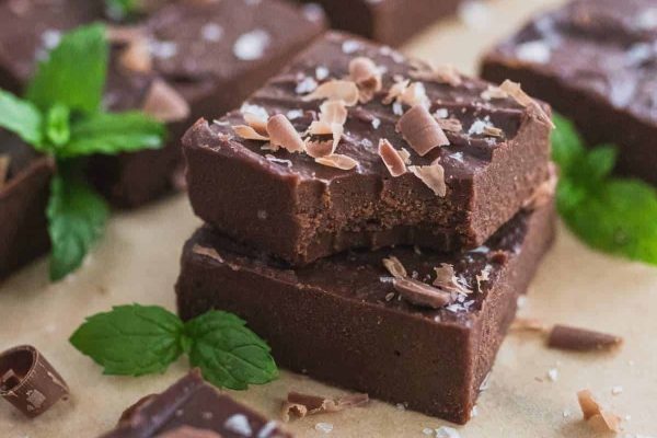 A stack of chocolate fudge with mint leaves on top.