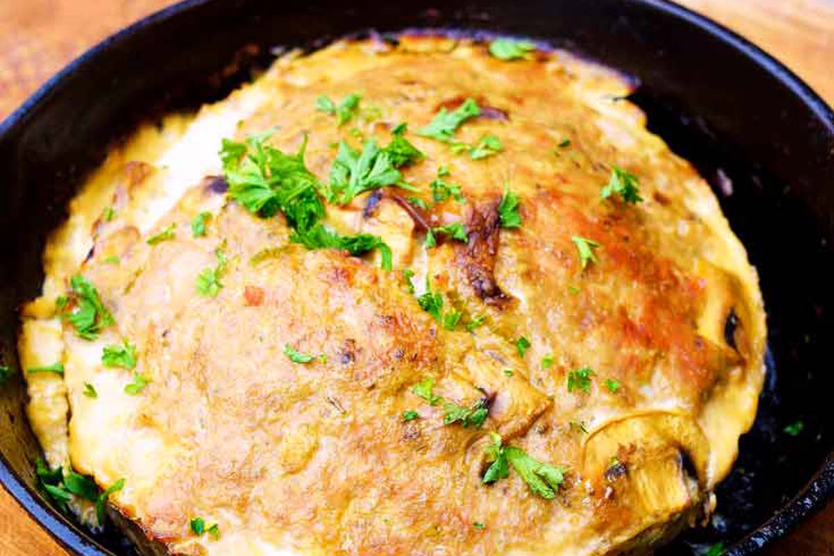 A roasted chicken in a skillet on a wooden table, perfect for those craving hearty meat dishes.
