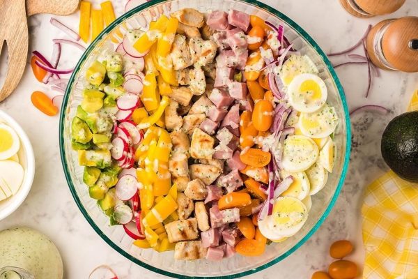 A bowl of salad with ham, eggs and vegetables.