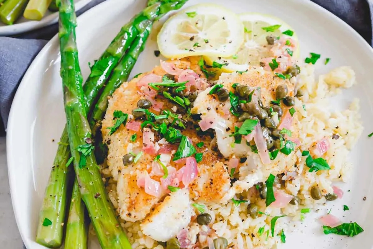 A plate of fish and asparagus on a white plate.