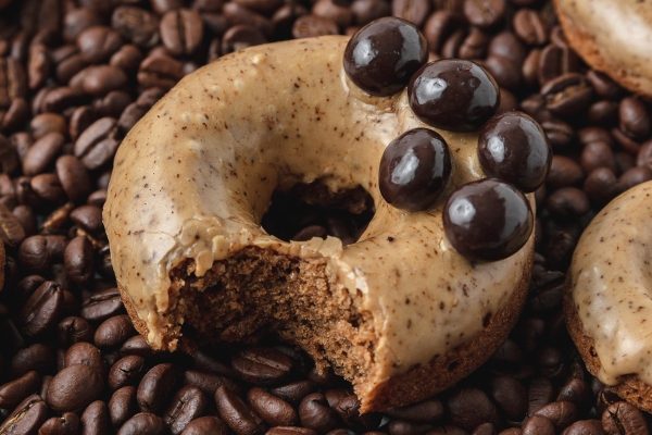 Donuts with chocolate icing on a bed of coffee beans.