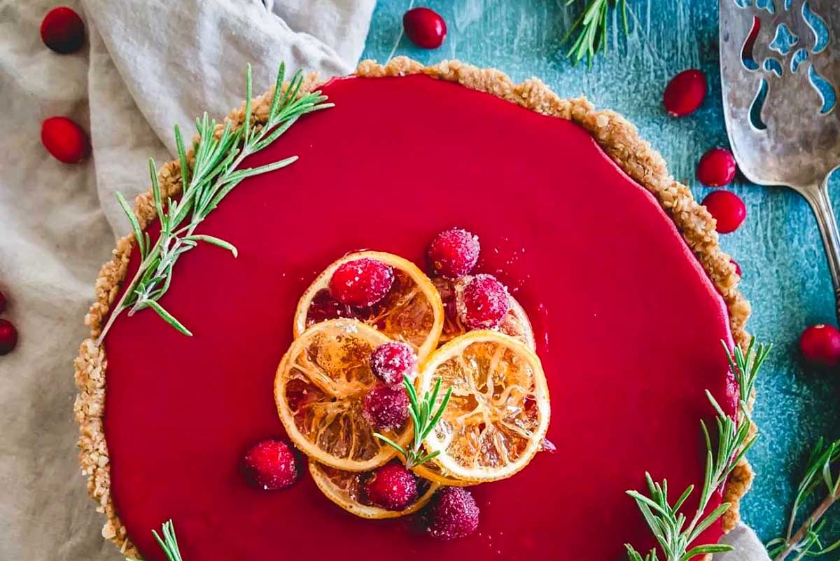 A festive cranberry tart adorned with cranberries and sprigs of rosemary, perfect for Friendsgiving.