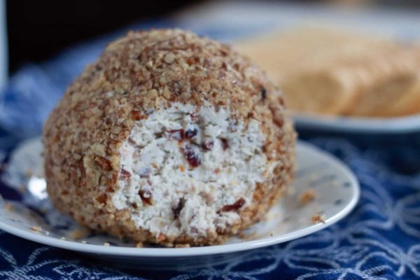 A cheese ball on a plate with crackers, perfect for serving at parties or gatherings.