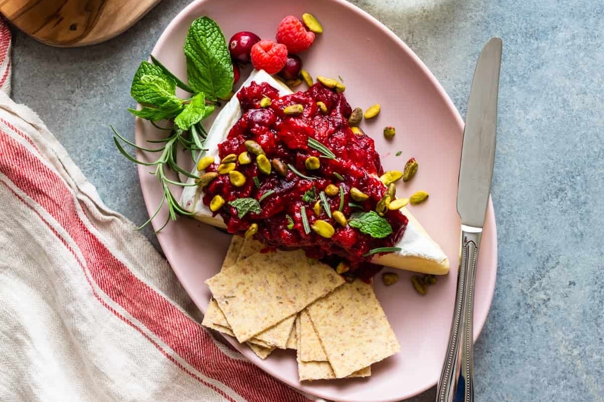 Appetizers: Cranberry and pistachio cheese with crackers on a pink plate for New Year's Eve.