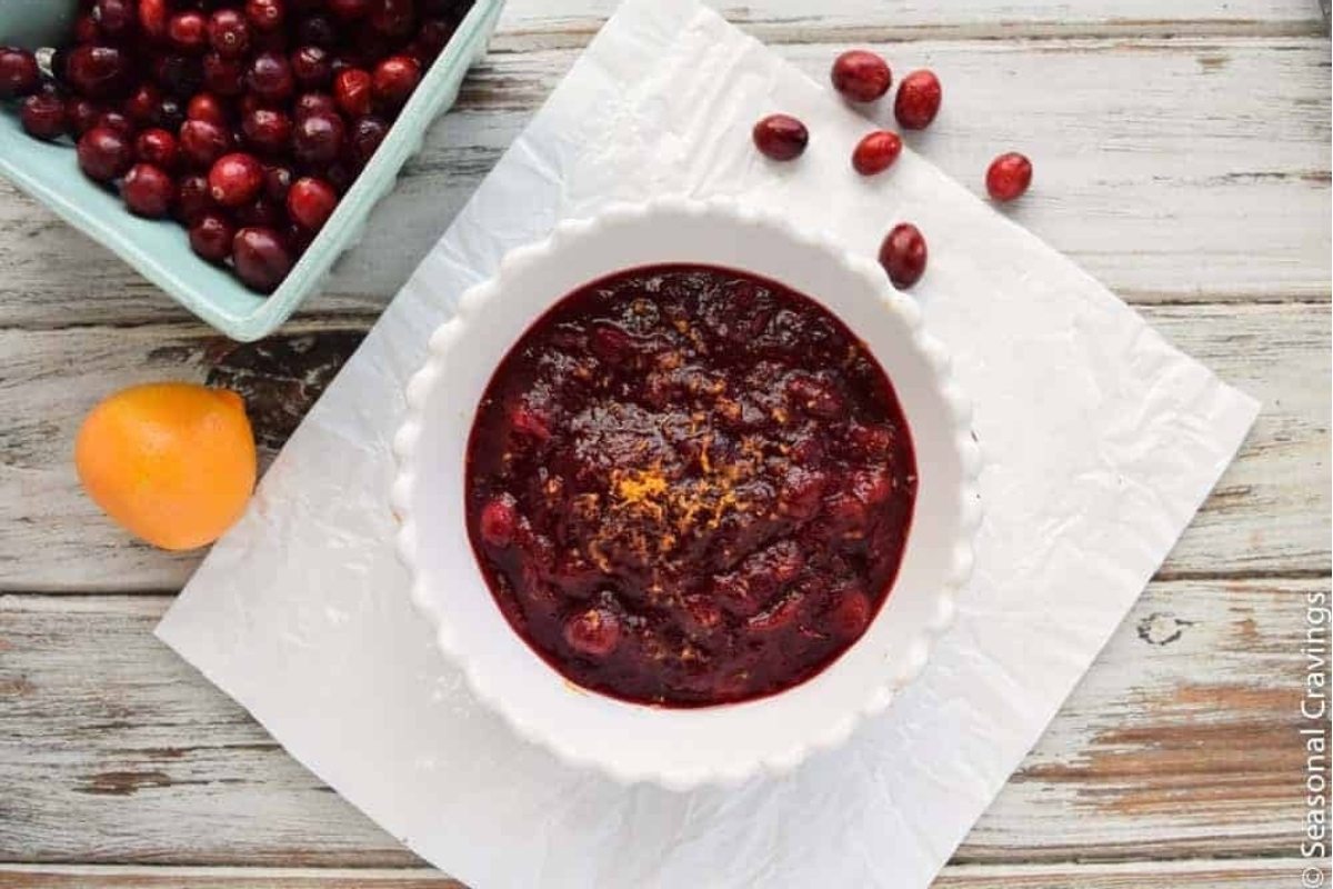 Cranberry sauce served in a bowl alongside fresh oranges.