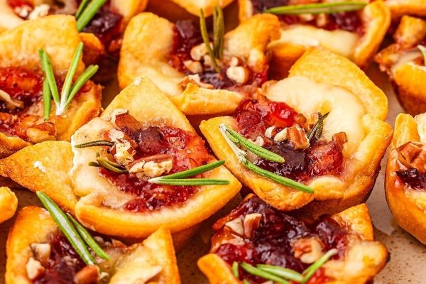 Cranberry cheesecake bites with rosemary sprigs.
