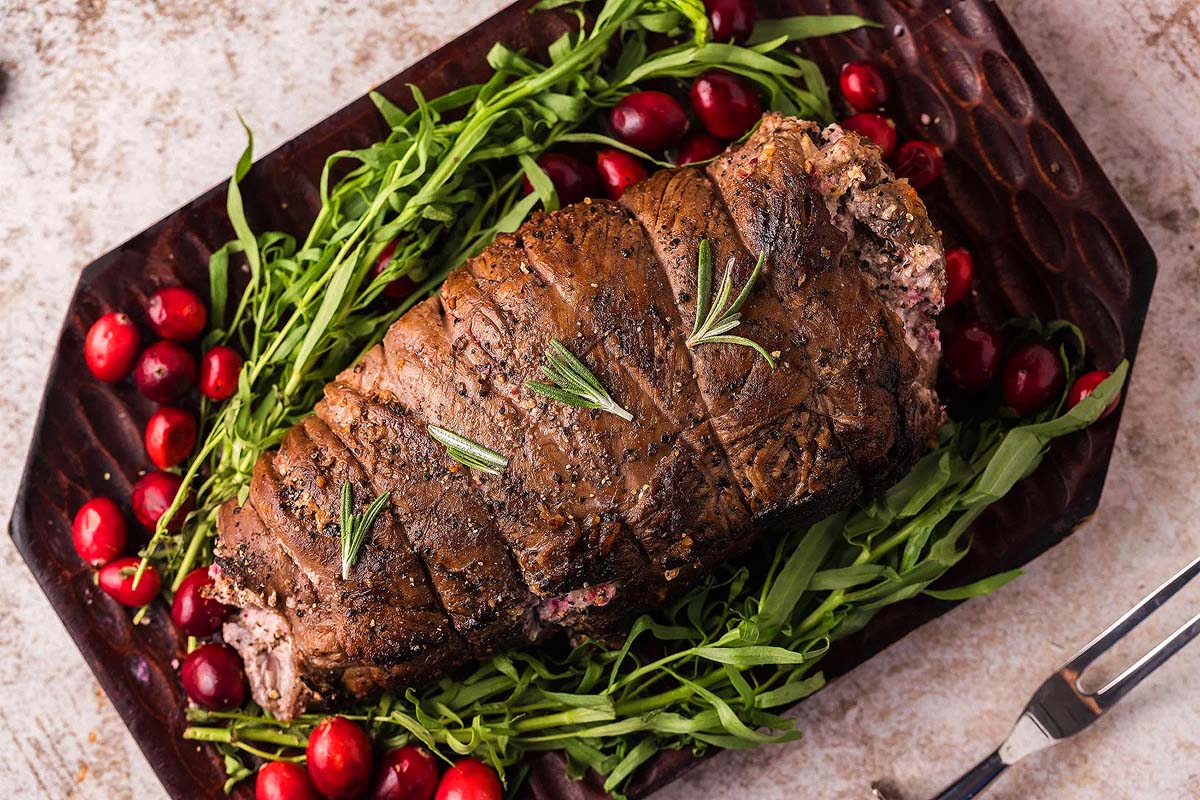 An appetizing Thanksgiving main dish featuring a flavorful roast accompanied by the delightful combination of cranberries and fresh herbs, all beautifully presented on a plate.
