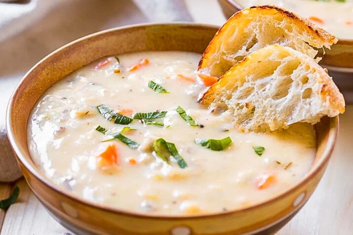 Two bowls of slow cooker soup with bread on top.