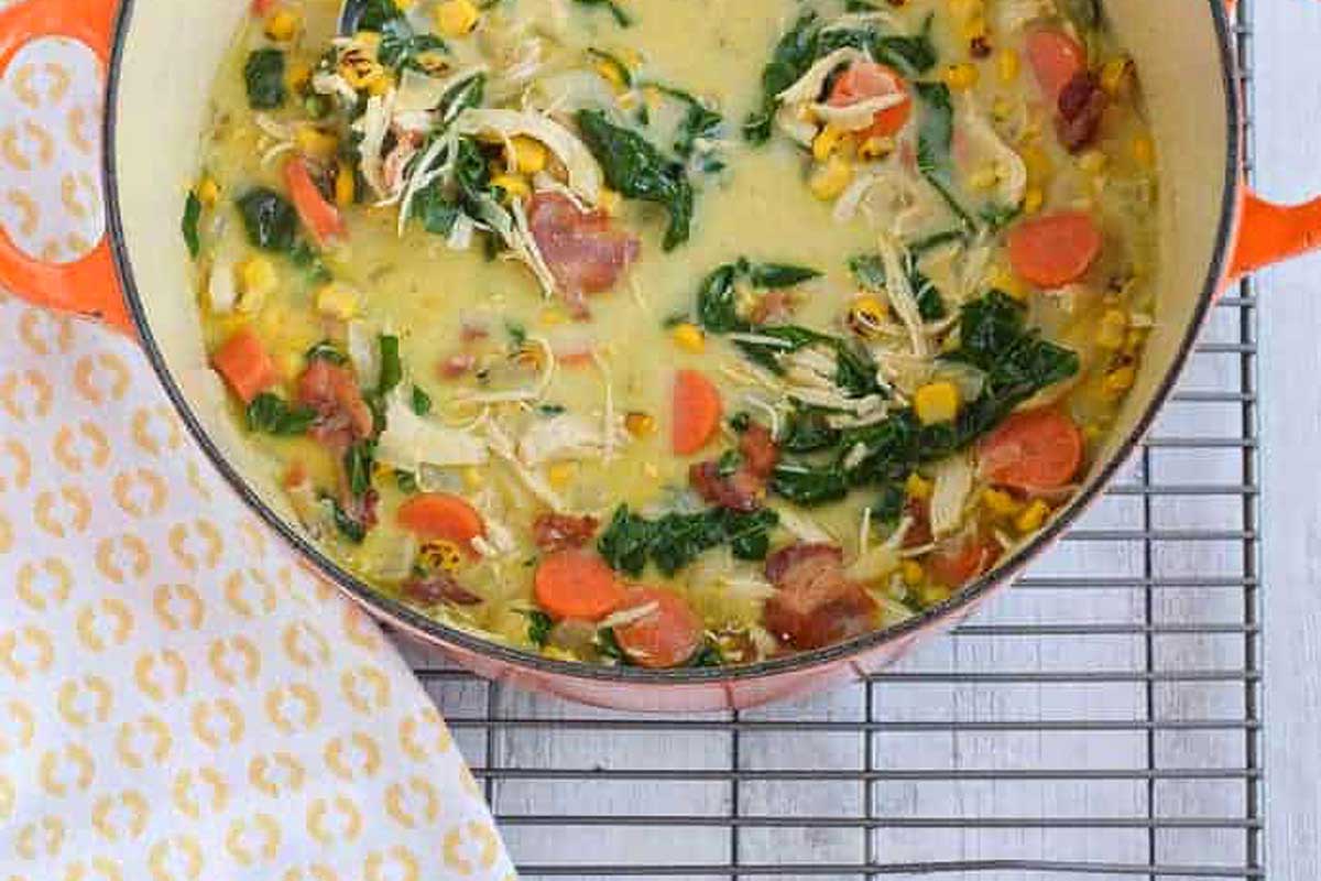 A pot of chicken and spinach soup on a cooling rack.
