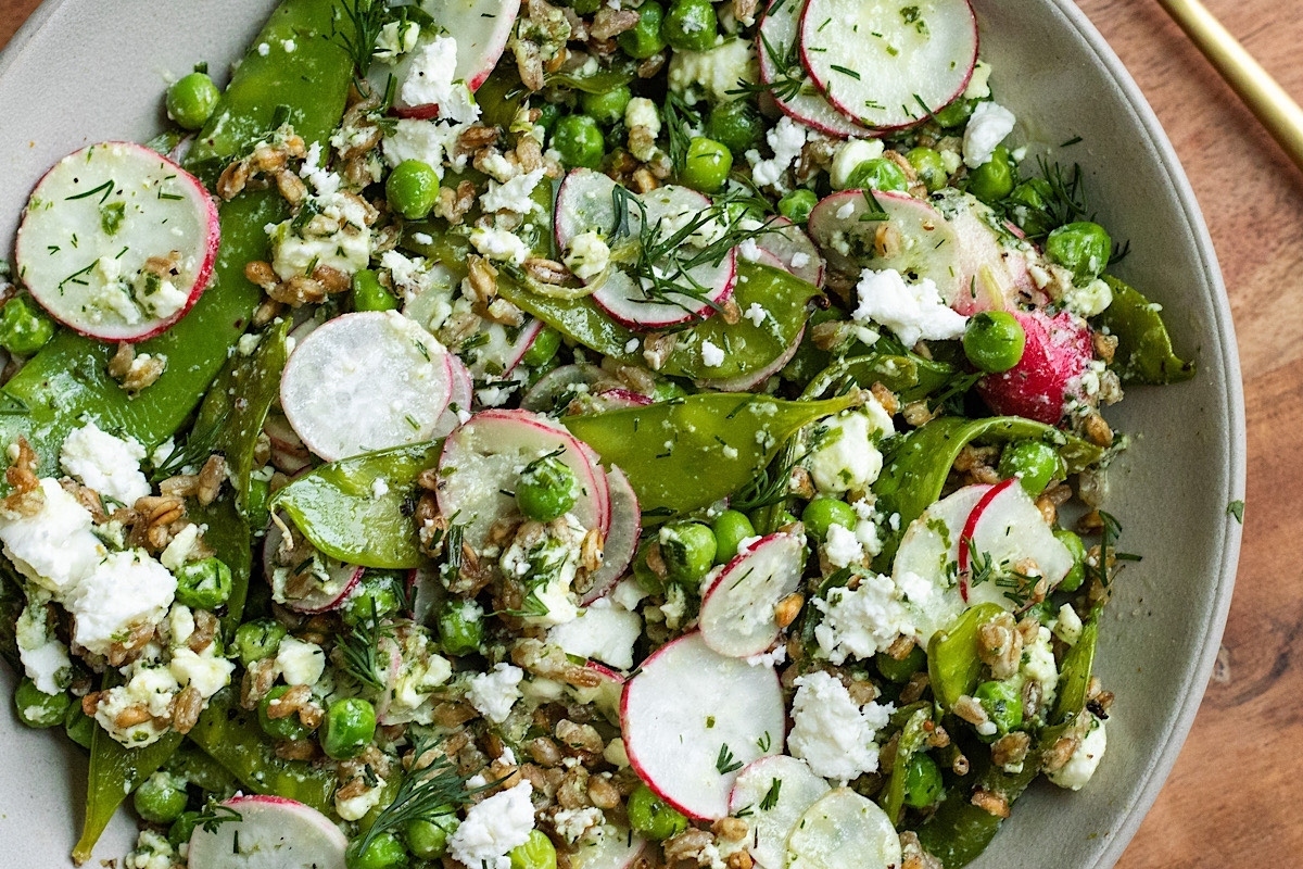 A bowl with frozen peas, radishes, and feta.