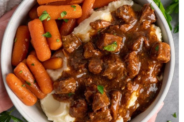 A hearty bowl of crockpot beef stew with tender chunks of beef, carrots, and creamy mashed potatoes.